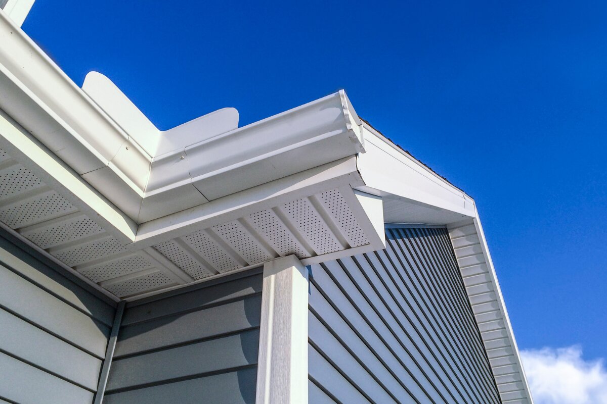 Detail of clean white K-style gutters with downspout